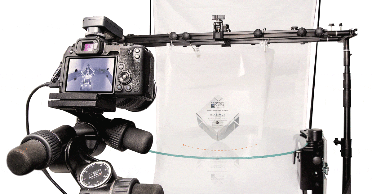 Camera targeting glass cube rotating on photo turntable.