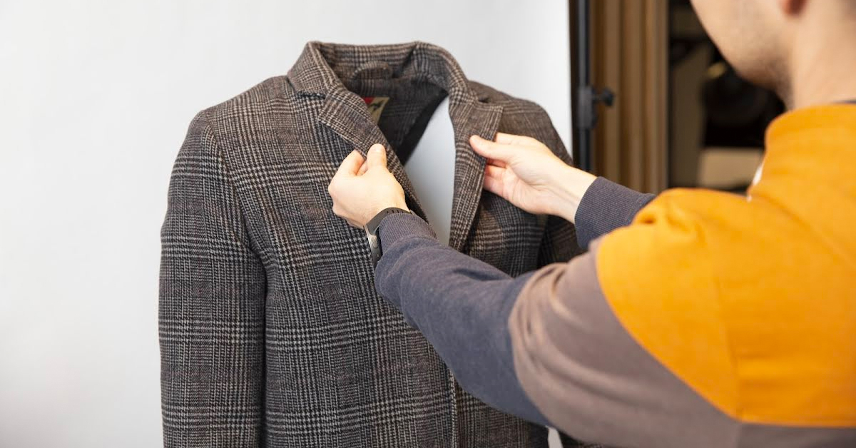 Photographer fitting men's jacket onto mannequin.