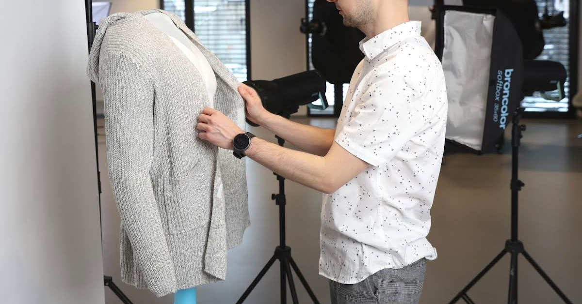 Photographer dressing mannequin in cardigan.