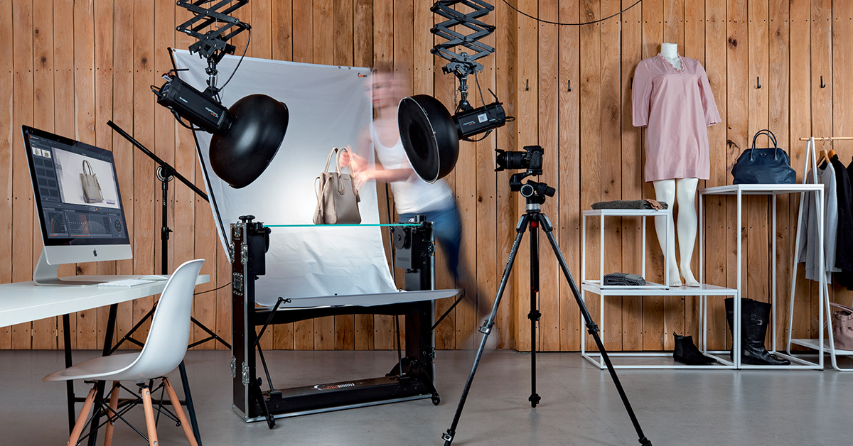 A product photographer prepares the workspace to photograph a line of fashion products
