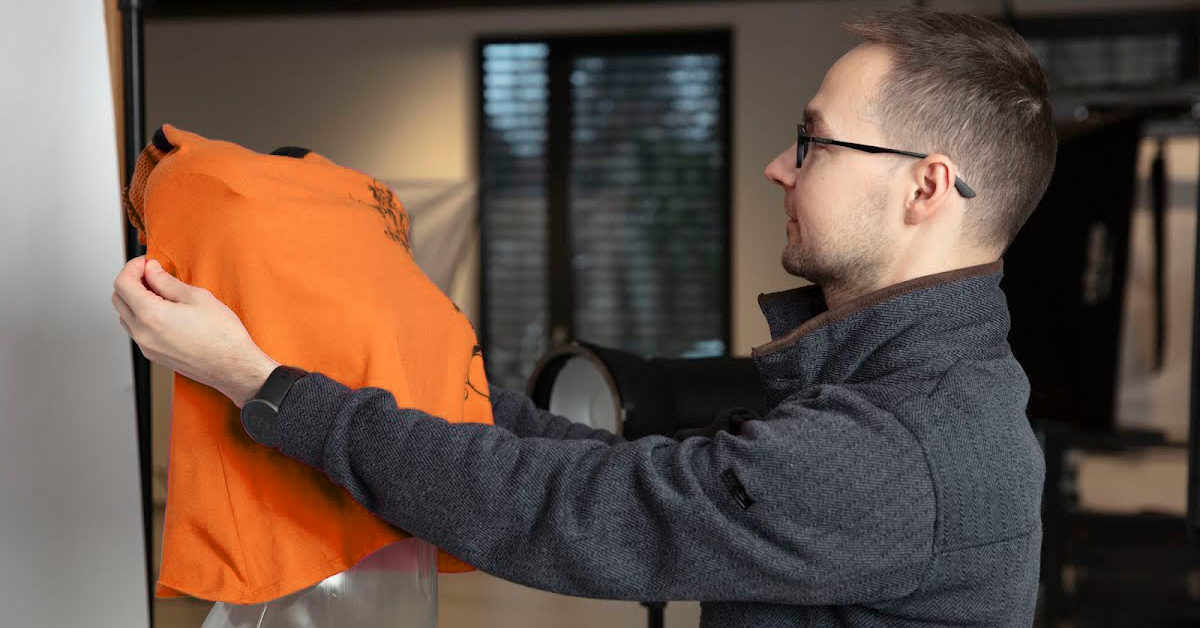 Photographer pulling dress down mannequin shoulders.