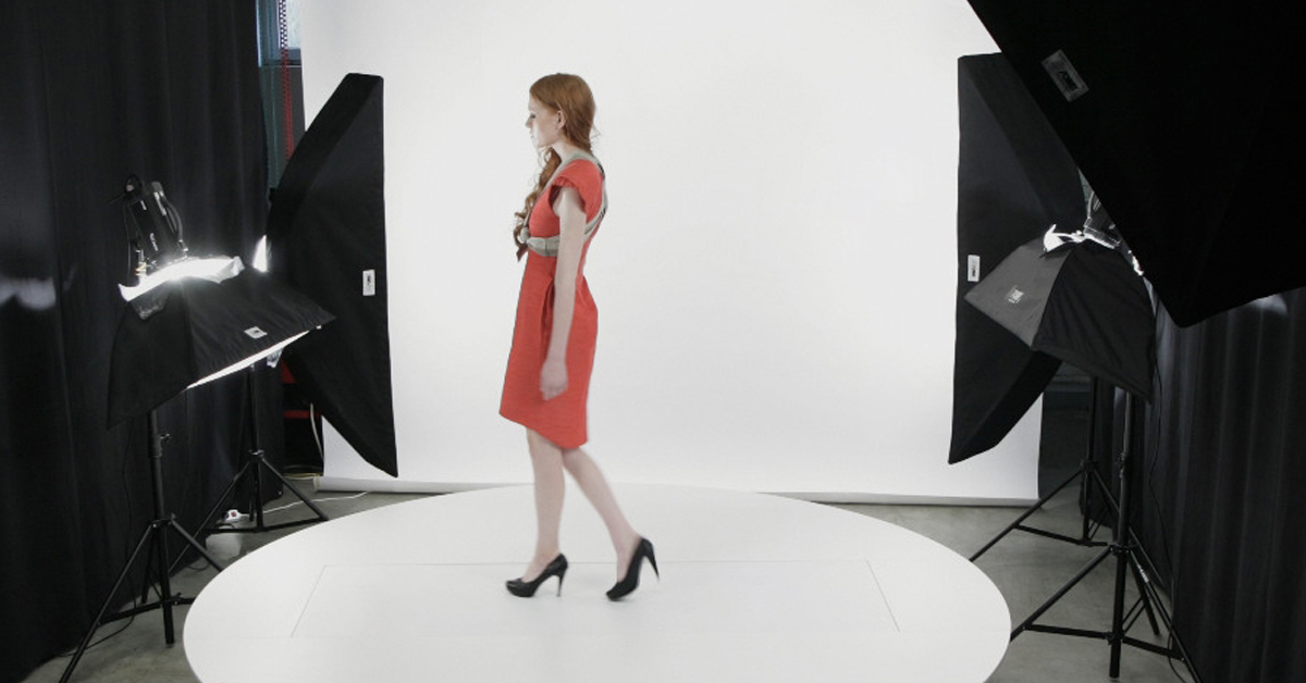 Model in red dress during photoshoot in studio.