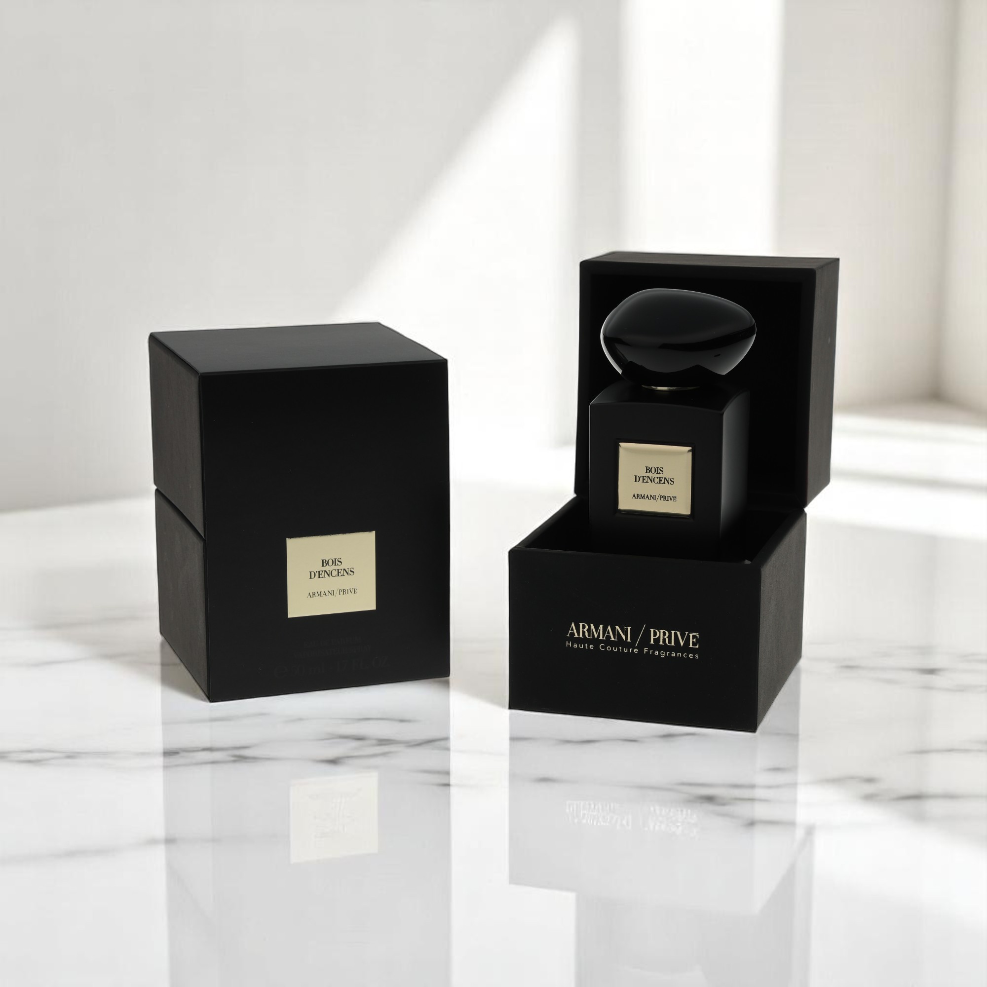 A packshot showcases black and gold Armani / Prive perfume on a marble table in a well-lit room.
